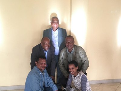 Group of five people posing for a photo in a room