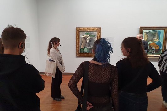 4 Personen von hinten vor einem gerahmten Gemälde im Museum