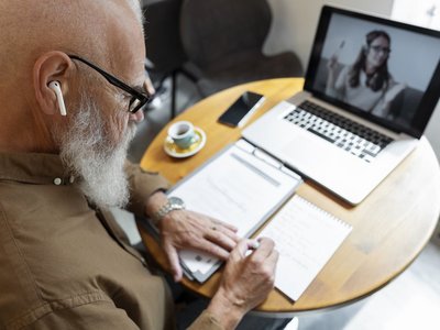 Mann macht sich Notizen während eines Videoanrufs