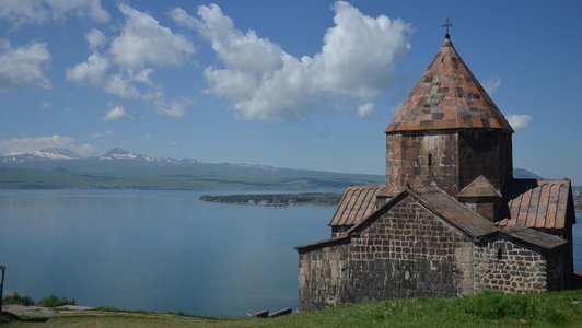 Church right on the waterfront of a blue lake and some snow covered mountains in the backgorund