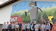  A class in front of a house wall with a spray paint mural.