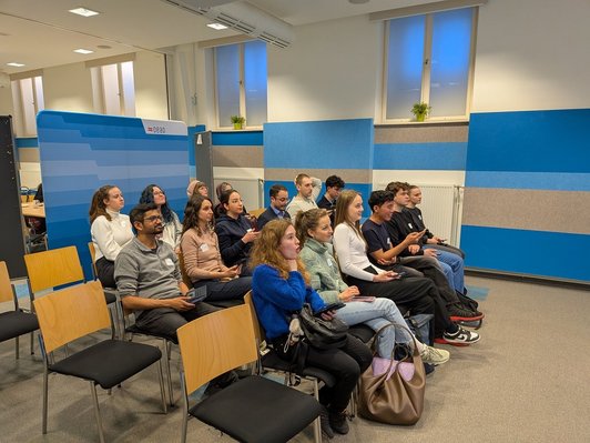 Photo of scholarship holders sitting in rows and participating in a quiz about Austria