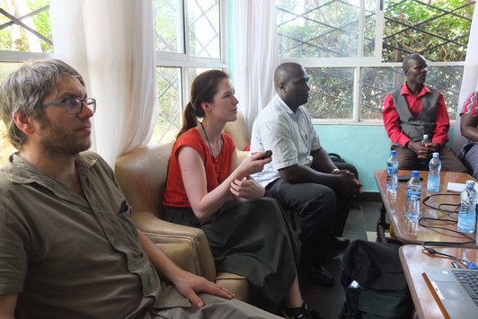 Group of people sitting and looking at something and one woman with a remote control in her hands