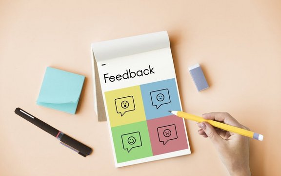 Block mit der Aufschrift "Feedback" und eine schreibende Hand