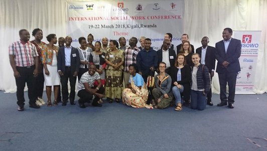 Big group of people posing for a group photo in front of a big conference information poster