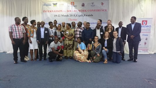 Big group of people posing for a group photo in front of a big conference information poster