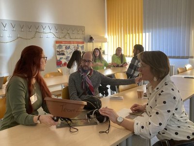 Workshopteilnehmende an Schreibtischen beim Reden