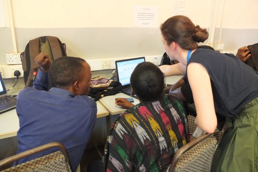 Group of people standing around a table and looking at a notebook