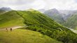 Landscape in the Caucasus Mountains with green meadows and mountains and two people.