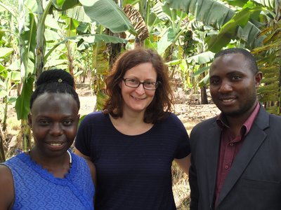 Two APPEAR scholars and one APPEAR representative posing for a photo in front of banana plants