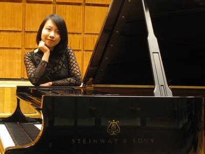 Eine Dame in einem schwarzen Kleid, die sich auf ein Steinway & Sons Klavier abstützt.