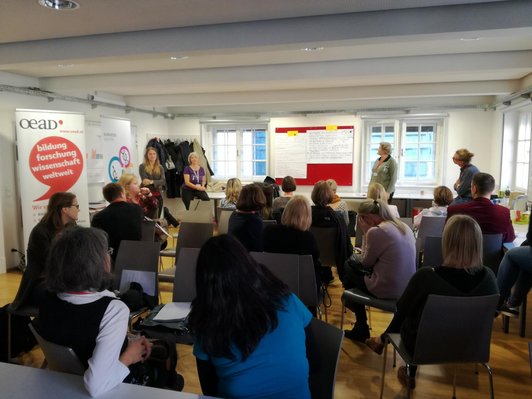 A seminar room filled with many people sitting on chairs.