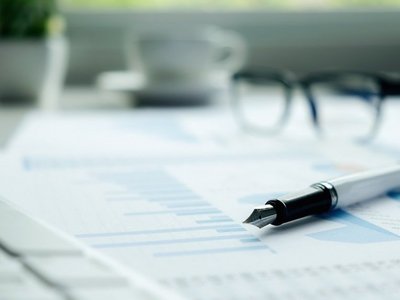 Business concept with copy space. Office desk table with pen focus and analysis chart, computer, notebook, cup of coffee on desk.Vintage tone retro filter, selective focus.