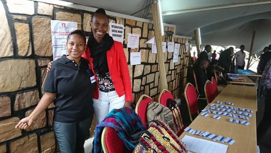 Two smiling women posing for a picture standing in a big tent