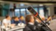 Microphone in the lecture hall. The focus is on the close-up of the microphone, while the seminar room behind it is blurred. Feedback