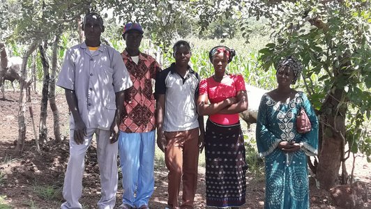 Five people standing under a tree posing for a photo