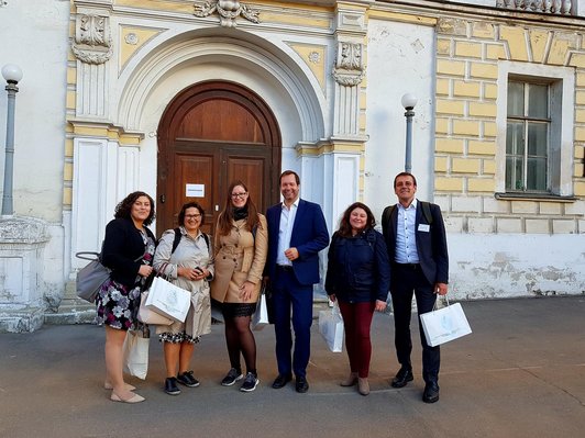 Gruppe von sechs Personen posiert vor einem Hochschulgebäude für ein Foto