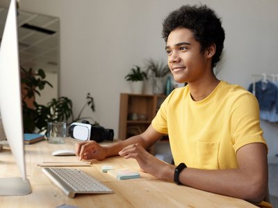 Jugendlicher in gelben T-Shirt vor einem Computer