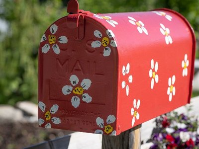 roter Briefkasten mit weißen Blümchen bemalt