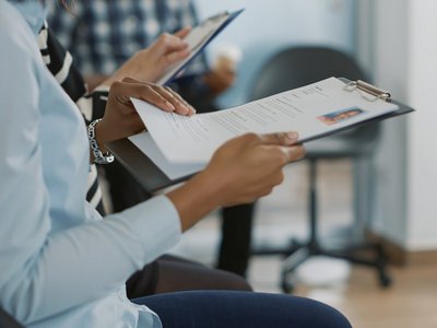Bewerber:innen mit Lebensläufen im Warteraum
