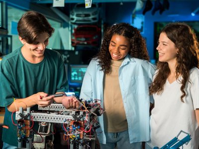 Drei Teenager arbeiten an einem Roboter