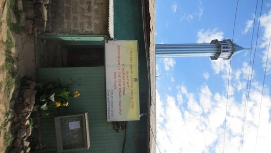 Green building with big information sign on it and a blue and white striped tower in the background