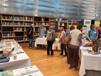 Messebesucher:innen an Ständen vor Bücherregalen