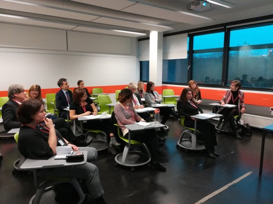 Group of people sitting on green chairs with integrated desks