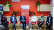 Austrian Federal President Alexander Van der Bellen sits with students and political representatives in a circle of chairs in front of a red-painted wall