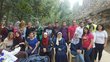 Group of people posing for a picture in frint of stone wall and trees