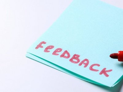 Das Wort Feedback steht in roter Schrift auf einem blauen Postit