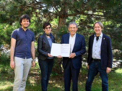 Vier Personen mit Vertrag vor einem Baum stehend
