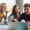 Eine Gruppe Student:innen sitzt um einen Laptop. 