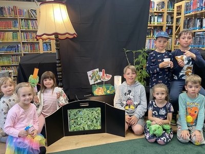 Gruppe Kinder am Boden vor Bücherregalen in Bibliothek
