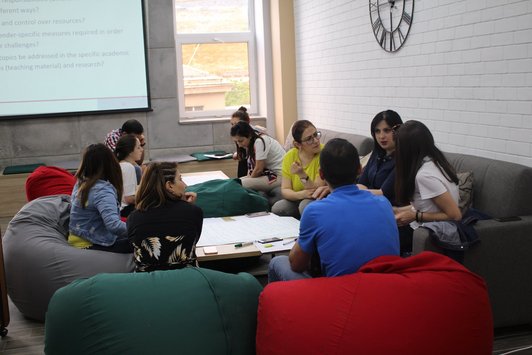 Group of people sitting on couches and beanbags around a table and talk to each other