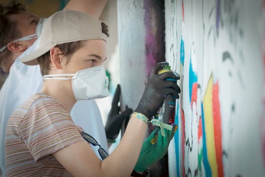 junge Menschen sprayen Graffiti auf eine Wand 