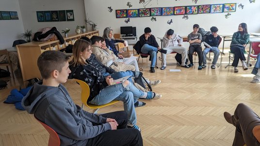 Schülerinnen und Schüler sitzen im Kreis