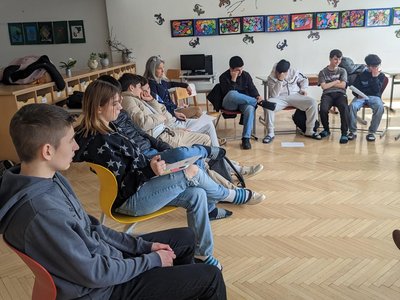 Schülerinnen und Schüler sitzen im Kreis