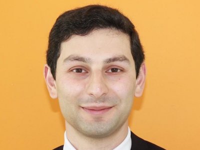 A formally dressed man standing in front of a yellow background