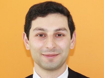 A formally dressed man standing in front of a yellow background