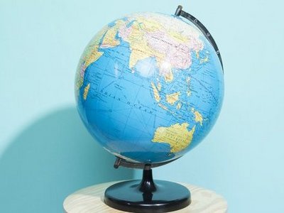 Globus steht vor einer hellblauen Wand auf einem kleinen, runden Tisch mit weißer Tischplatte