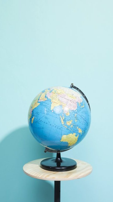 Globus steht vor einer hellblauen Wand auf einem kleinen, runden Tisch mit weißer Tischplatte