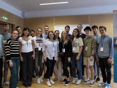 Gruppe an jungen Menschen stehen in einem Raum und schauen in die Kamera