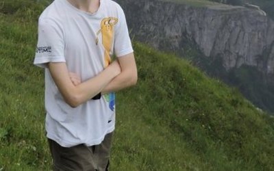 Ernst Mach Ukraine Stipendiat Ivan Solovei steht auf einem Berg, hinter ihm eine weite Aussicht auf die Landschaft und einen See im Tal