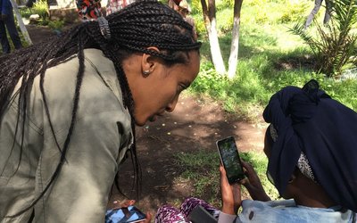 Two women with mobile phones in their hands are talking to each other