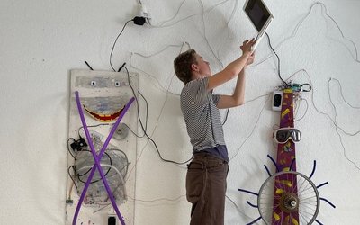 Ein junger Mann programmiert vor einem Kunstwerk