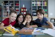 Kinder lächeln für ein Gruppenfoto in die Kamera, vor ihnen liegen Bücher