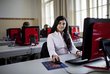 Mädchen sitzt in einer Schule vor einem Computer und sieht in die Kamera