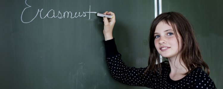 Mädchen schreibt mit Kreide Erasmus+ auf Schultafel