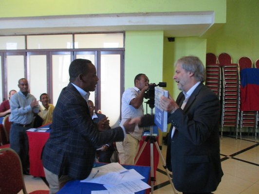 Two man shaking their hands and handing over a book